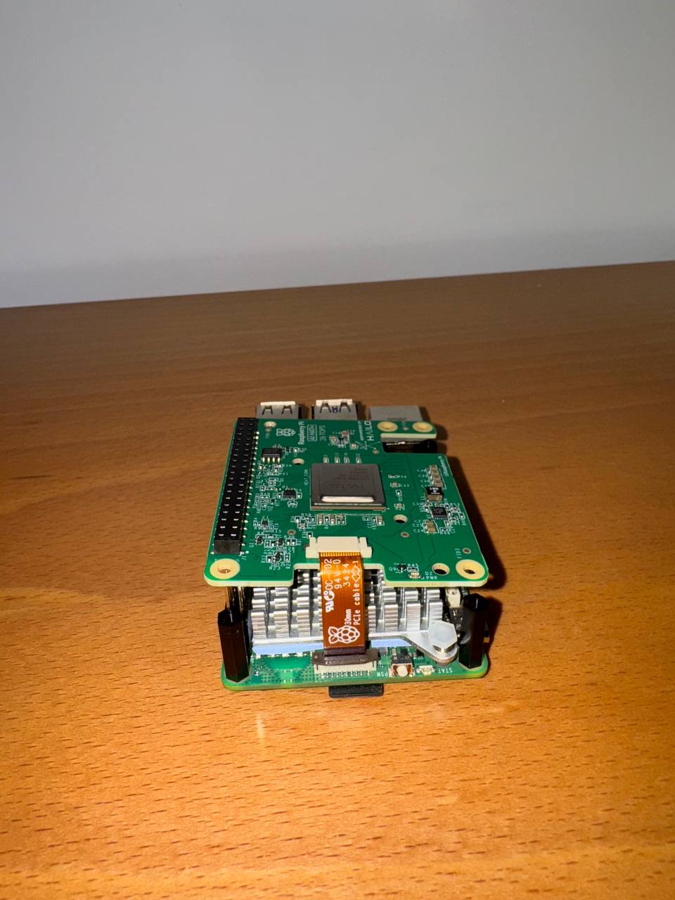 Disconnect the ribbon cable from the AI HAT+, and insert the other end into the PCIe port of your Raspberry Pi.